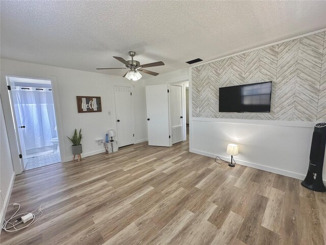 unfurnished living room with ceiling fan, light hardwood / wood-style floors, and a textured ceiling