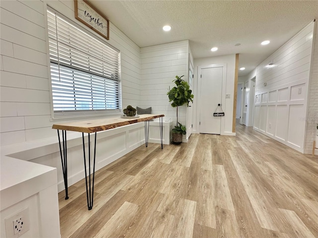 foyer entrance featuring light hardwood / wood-style floors, a textured ceiling, and wood walls