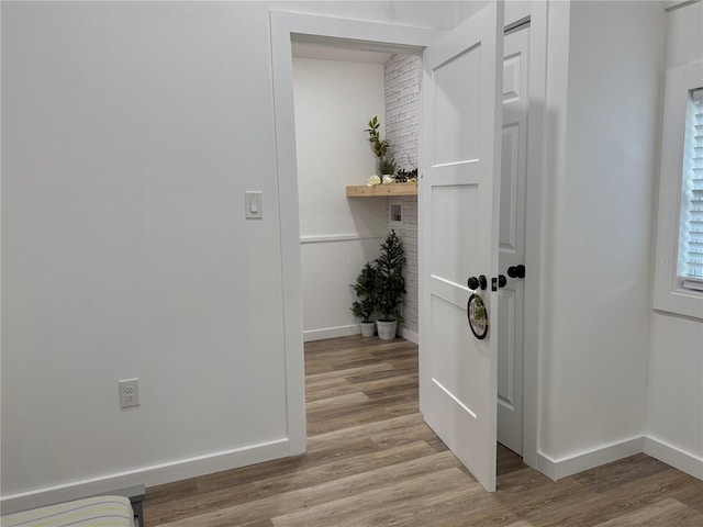 hall featuring light wood-style flooring and baseboards