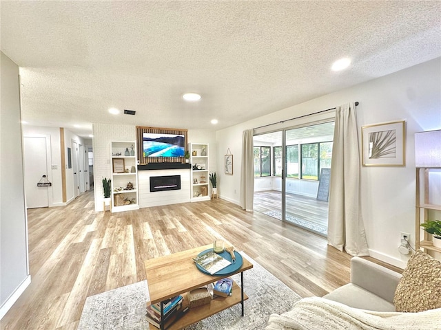 living area with a large fireplace, a textured ceiling, and light wood-type flooring
