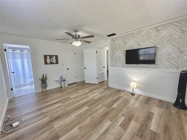 unfurnished living room with baseboards, visible vents, ceiling fan, a textured ceiling, and light wood-type flooring