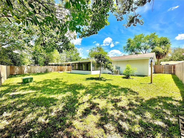 view of yard featuring a sunroom and a fenced backyard