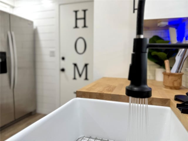 interior details with light countertops, a sink, and stainless steel refrigerator with ice dispenser