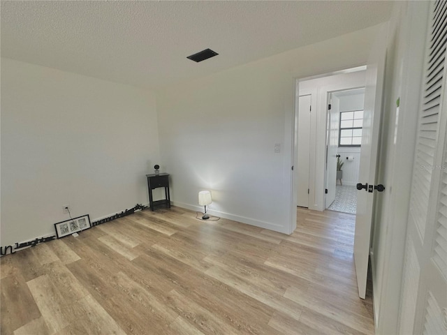 laundry area with a textured ceiling, baseboards, and light wood-style floors