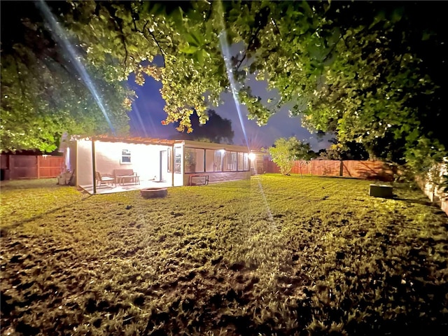 back of house at dusk featuring a patio, a lawn, and a fenced backyard