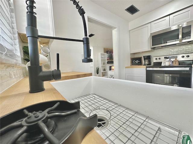 kitchen featuring visible vents, light countertops, backsplash, appliances with stainless steel finishes, and white cabinetry