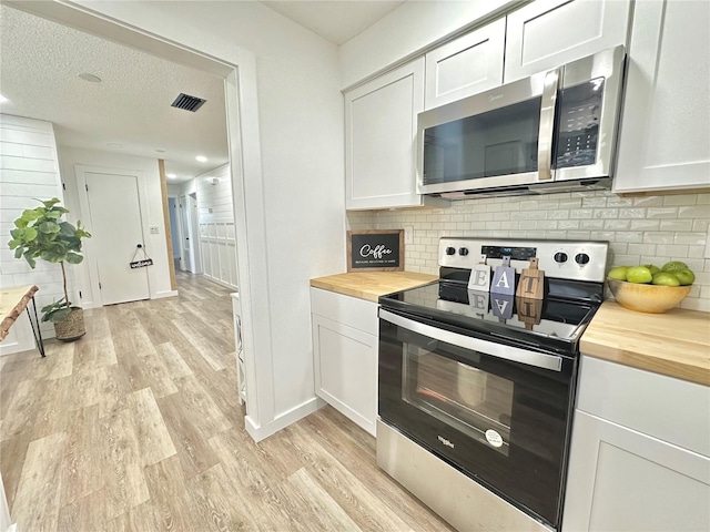 kitchen with appliances with stainless steel finishes, butcher block counters, and white cabinetry