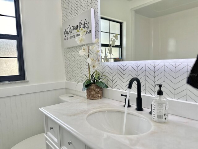 bathroom with a wainscoted wall, toilet, and vanity