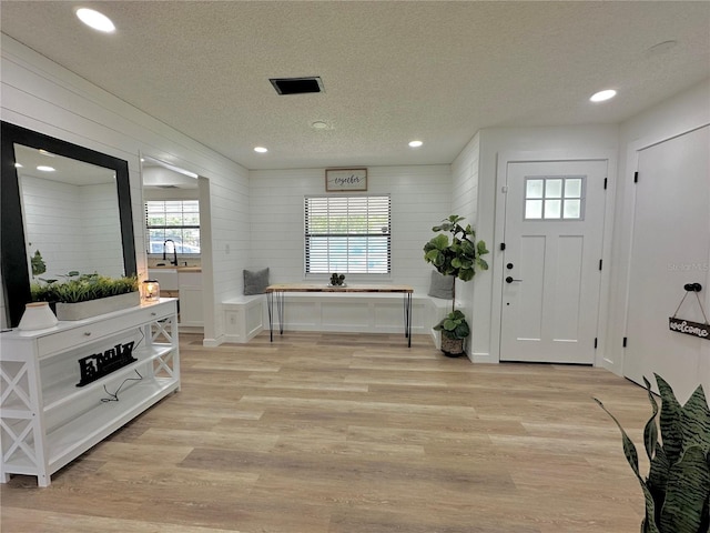 foyer featuring light wood-type flooring, visible vents, a textured ceiling, and recessed lighting