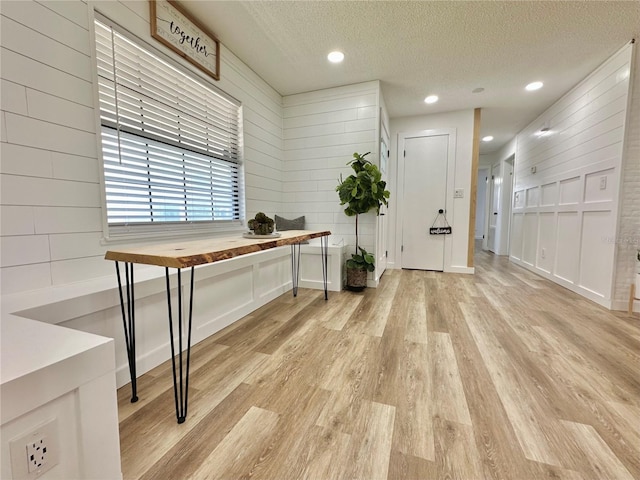 office with a textured ceiling, wooden walls, recessed lighting, and light wood-style floors