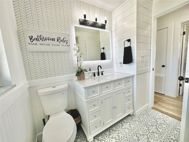bathroom with visible vents, toilet, tile patterned flooring, vanity, and tile walls