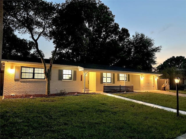 single story home with an attached garage, a yard, brick siding, and concrete driveway