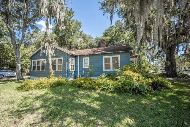 view of front of house with central AC unit and a front yard