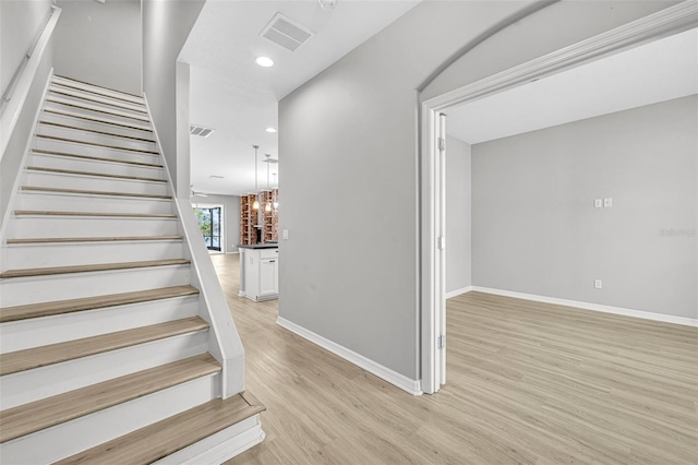 stairs featuring hardwood / wood-style floors and a chandelier