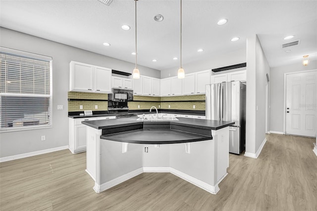 kitchen with white cabinets, a kitchen island with sink, sink, and appliances with stainless steel finishes