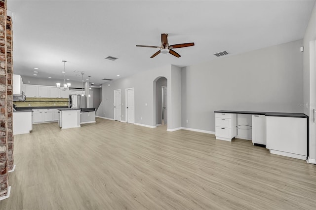 unfurnished living room featuring ceiling fan with notable chandelier and light wood-type flooring