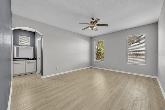 empty room with a textured ceiling, light hardwood / wood-style floors, and ceiling fan