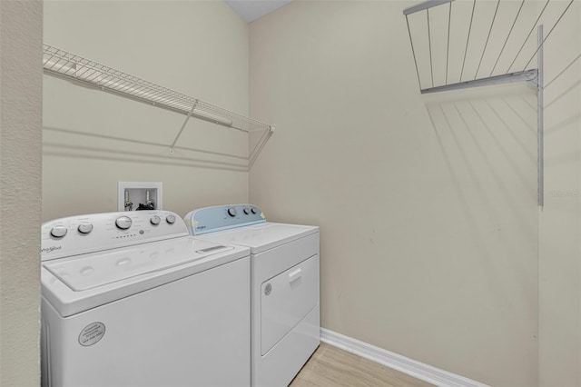 laundry area with washer and clothes dryer and light hardwood / wood-style floors