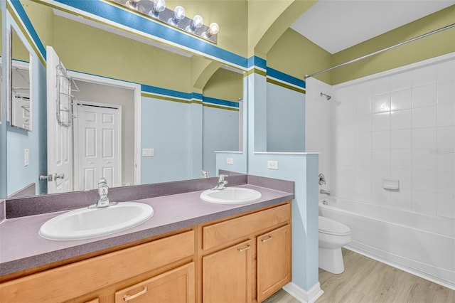 full bathroom featuring vanity, hardwood / wood-style flooring, toilet, and tiled shower / bath combo