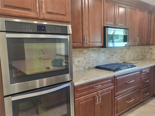 kitchen with tasteful backsplash, appliances with stainless steel finishes, and light stone countertops