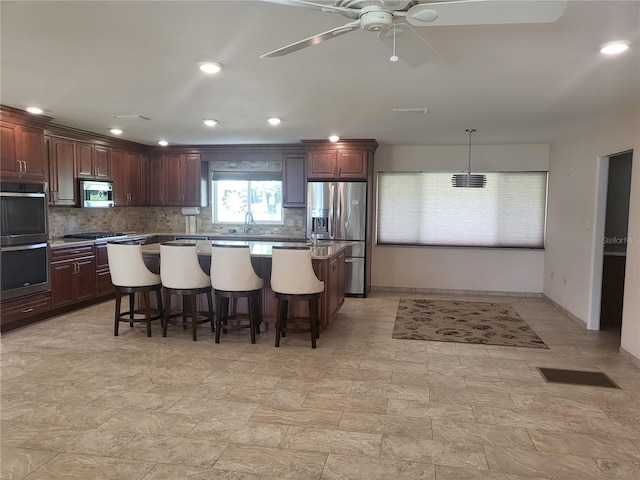 kitchen featuring a breakfast bar, sink, hanging light fixtures, a kitchen island, and stainless steel appliances