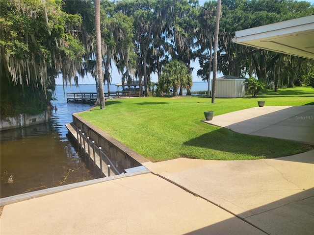 exterior space with a water view, a dock, and a lawn