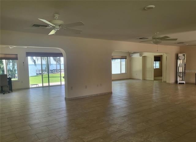 unfurnished room with a water view, ceiling fan, and an AC wall unit