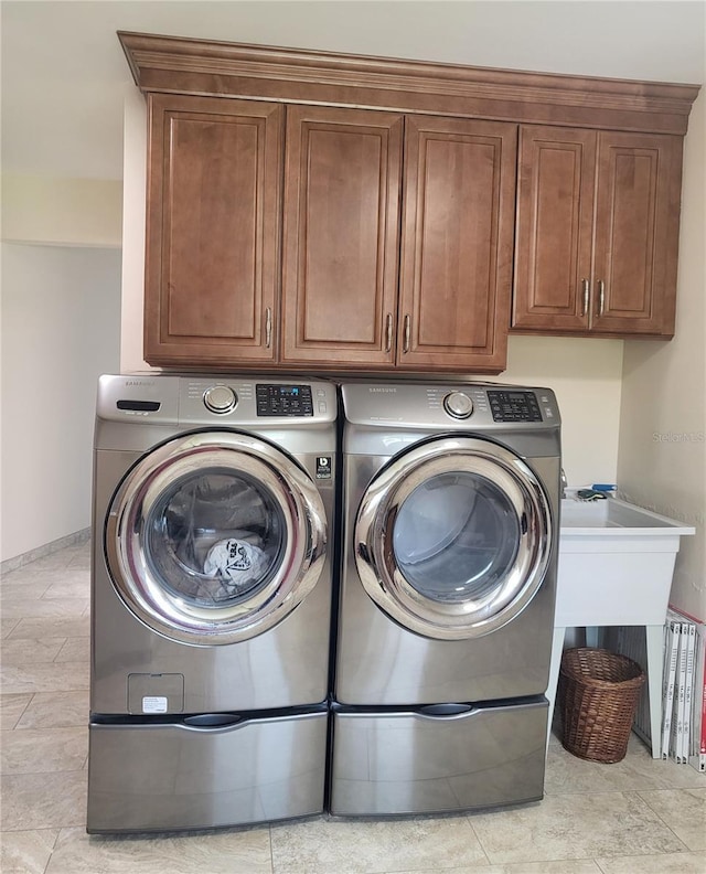 clothes washing area with cabinets and washing machine and dryer