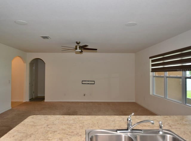 kitchen featuring ceiling fan, carpet floors, and sink