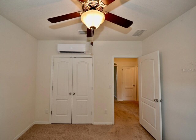 unfurnished bedroom featuring ceiling fan, light colored carpet, a closet, and an AC wall unit