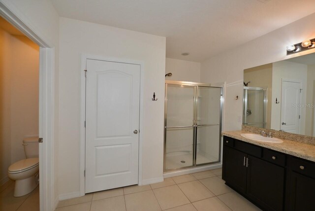 bathroom featuring vanity, a shower with shower door, tile patterned floors, and toilet