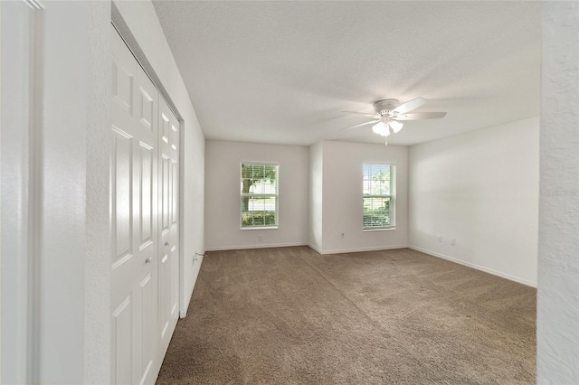 carpeted empty room with ceiling fan and a textured ceiling