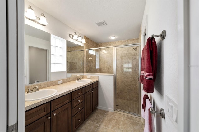 bathroom with tile patterned flooring, vanity, a shower with door, and a textured ceiling