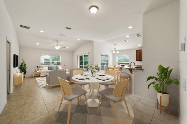 tiled dining room with ceiling fan with notable chandelier and lofted ceiling