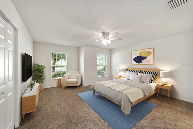 carpeted bedroom featuring ceiling fan and a textured ceiling