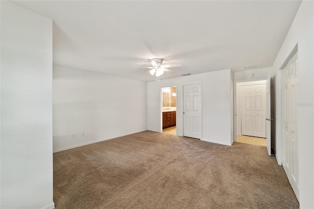 unfurnished bedroom with ceiling fan, light colored carpet, and ensuite bathroom