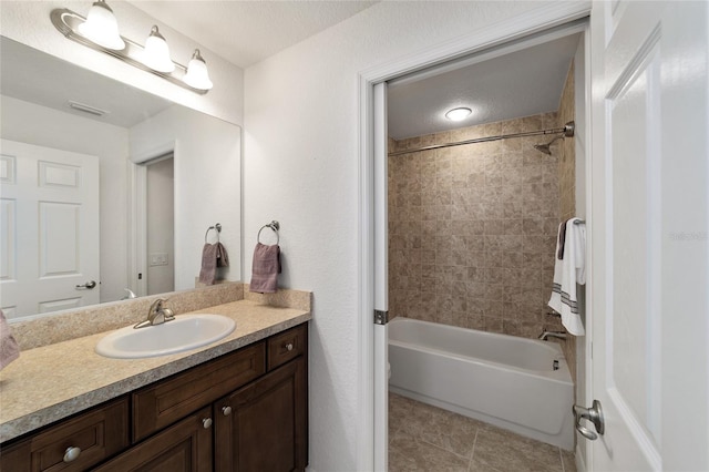 bathroom featuring a textured ceiling, vanity, and tiled shower / bath combo