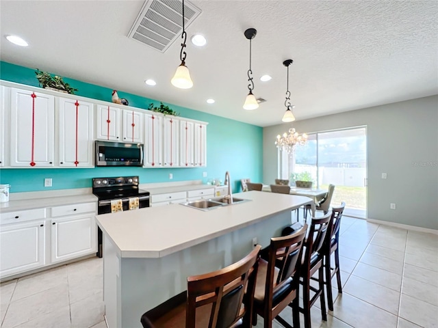 kitchen featuring stainless steel appliances, a center island with sink, light tile flooring, hanging light fixtures, and sink