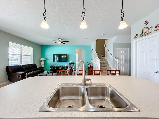 kitchen featuring hanging light fixtures, ceiling fan, sink, and a textured ceiling