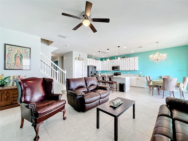 tiled living room with a textured ceiling and ceiling fan with notable chandelier