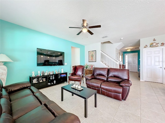 living room featuring light tile flooring, ceiling fan, and a textured ceiling