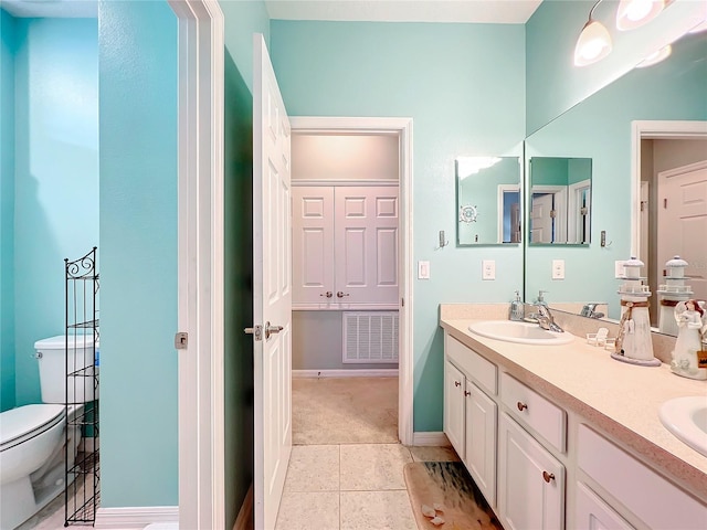 bathroom with tile flooring, dual sinks, toilet, and vanity with extensive cabinet space