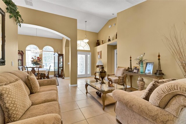 living room featuring light tile patterned flooring, a notable chandelier, and high vaulted ceiling