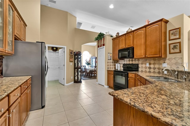 kitchen featuring backsplash, light stone counters, sink, black appliances, and light tile patterned flooring