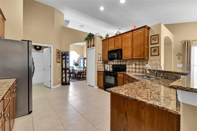 kitchen featuring tasteful backsplash, sink, black appliances, stone counters, and light tile patterned flooring