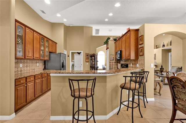 kitchen with a breakfast bar, light stone countertops, kitchen peninsula, and stainless steel appliances