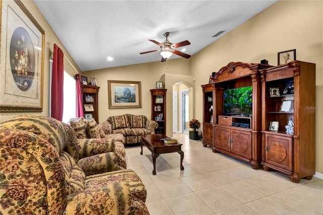 living room with ceiling fan, lofted ceiling, a textured ceiling, and light tile patterned floors