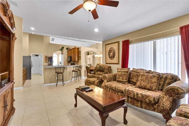 living room with ceiling fan, light tile patterned flooring, and a textured ceiling