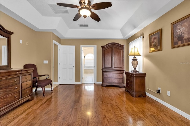 sitting room featuring a raised ceiling, ceiling fan, and light hardwood / wood-style flooring