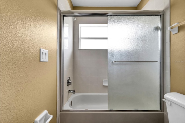 bathroom with toilet and bath / shower combo with glass door